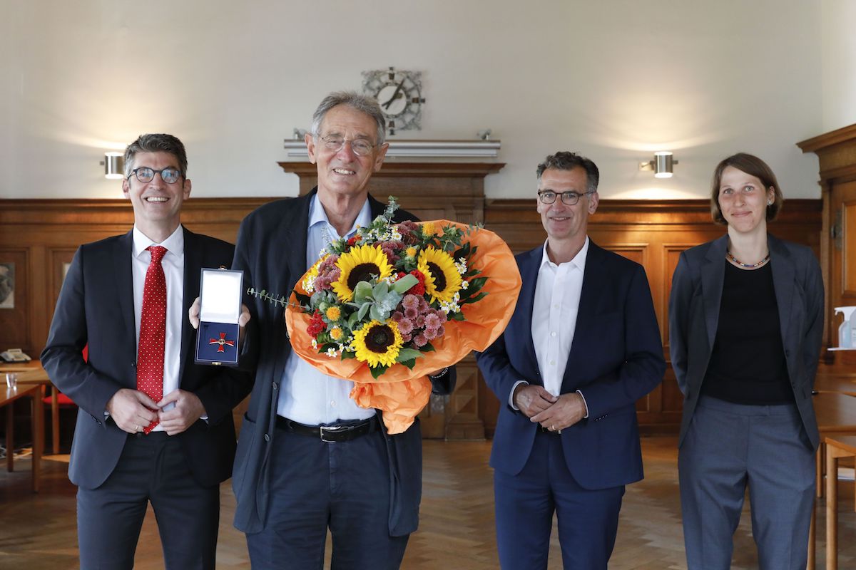 Prof. Dr. Dr. Reinhard Loose (mit Blumen) nimmt die Glückwünsche von Prof. Dr. Michael Lell (links), Prof. Dr. Achim Jockwig (2. von rechts) und Dr. Josefin Ammon entgegen (© Giulia Iannicelli/Klinikum Nürnberg)